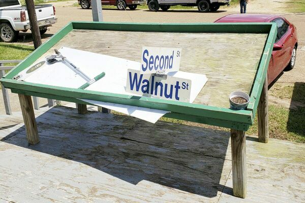 The intersection sign for Second and Walnut streets in Meadville sits on a table in front of Sullivan's Kitchen and Produce after thunderstorm winds damaged the front of the business. (Photo by Duane Simpson)