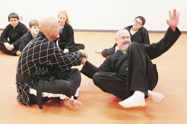 Simpson Hapkido owner-instructor Duane Simpson (left) demonstrates a self-defense take-down technique using joint manipulation on adult student Bart Houston (right).